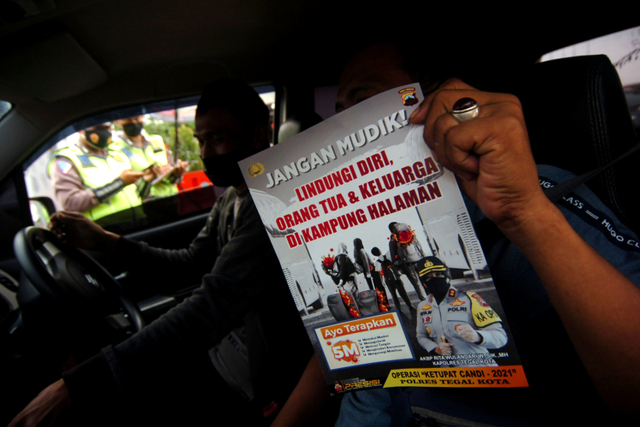 Pengendara menunjukkan brosur "jangan mudik" saat penyekatan mudik di jalur Pantura Tegal, Jawa Tengah.  Foto: Oky Lukmansyah/ANTARA FOTO