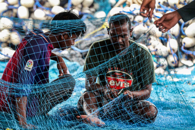 Sejumlah nelayan memperbaiki jaring saat terjadi gelombang tinggi di Tempat Pendaratan Ikan (TPI) Pusong, Lhokseumawe, Aceh, Jumat (28/5/2021). Foto: Rahmad/ANTARA FOTO