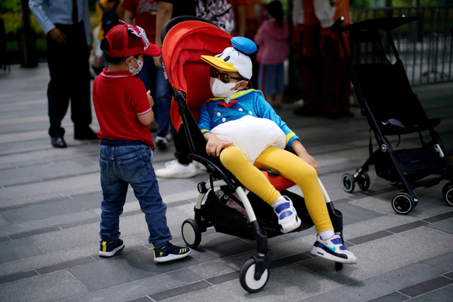 Anak-anak memakasi masker saat mengunjungi Shanghai Disney Resort di Shanghai, China.  Foto: Aly Song/REUTERS