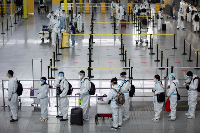 Ilustrasi penumpang menggunakan APD di bandara Selasa (1/6). Foto: Eloisa Lopez/Reuters