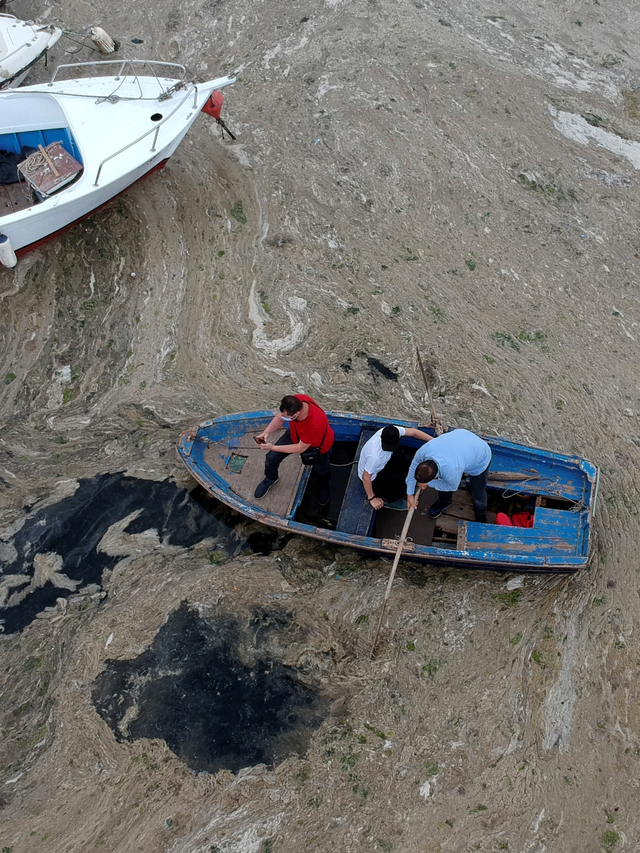 Sejumlah orang berdiri di atas perahu yang dikelilingi oleh wabah ingus laut di pelabuhan Pendik, Laut Marmara Turki. Foto: AP Photo