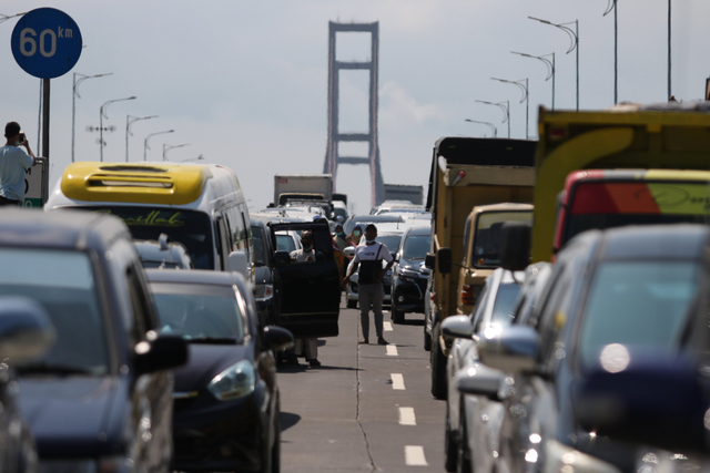 Sejumlah warga dari Pulau Madura keluar dari mobilnya saat mengantre masuk ke Surabaya di akses keluar Jembatan Suramadu, Surabaya, Minggu (6/6/2021). Foto: Didik Suhartono/Antara Foto