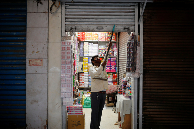 Seorang penjaga toko membuka tokonya ketika pihak berwenang melonggarkan pembatasan di New Delhi, India, Senin (7/6).  Foto: Adnan Abidi/REUTERS