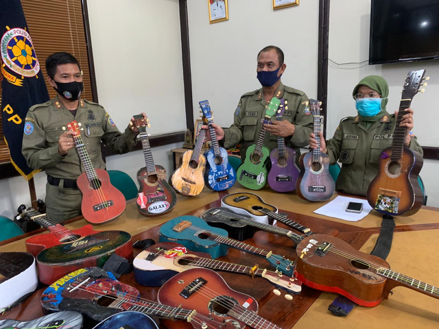 Kepala Satpol PP Kota Pontianak, Syarifah Adriana (kanan), bersama stafnya menunjukkan gitar-gitar milik pengamen yang terjaring razia. Foto: Teri/Hi!Pontianak
