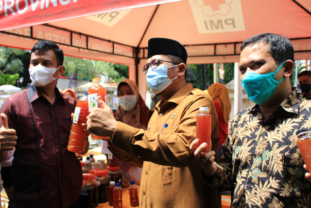 Wali Kota Padang Hendri Septa (tengah) yang didampingi oleh Direktur Bank Sampah Syaifuddin Islami (kanan) memperlihatkan eco enzyme yang diproduksi oleh Bank Sampah Unit Andalas Sepakat, Selasa 8 Juni 2021. Foto: Langkan/Kumparan