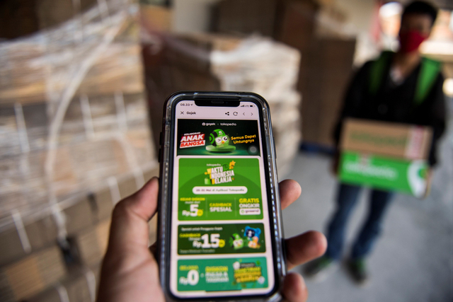 Pengemudi daring Gojek membawa kemasan paket dari Tokopedia di Titipaja Warehouse, Jakarta, Jumat (28/5/2021). Foto: M Agung Rajasa/Antara Foto