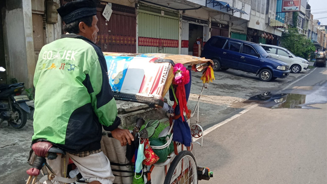 Abah Bojes menarik becak mengenakan jaket ojol. (Foto: @tama28nda/Twitter)