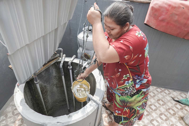 Warga memeriksa air sumur yang telah dibersihkan oleh tim dari Pertamina RU IV Cilacap, di Kelurahan Kutawaru, Cilacap Tengah, Cilacap, Jateng, Minggu (13/6/2021). Foto: Idhad Zakaria/ANTARA FOTO