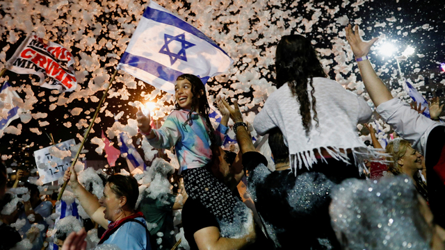 Orang-orang berselebrasi setelah parlemen Israel memberikan suara dalam pemerintahan koalisi baru, di Rabin Square di Tel Aviv, Israel, Minggu (13/6). Foto: Corinna Kern/REUTERS