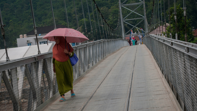Warga melintas di jembatan gantung yang telah dibangun di Desa Banjar Irigasi, Lebak, Banten, Selasa (15/6/2021). Foto: Muhammad Bagus Khoirunas/ANTARA FOTO