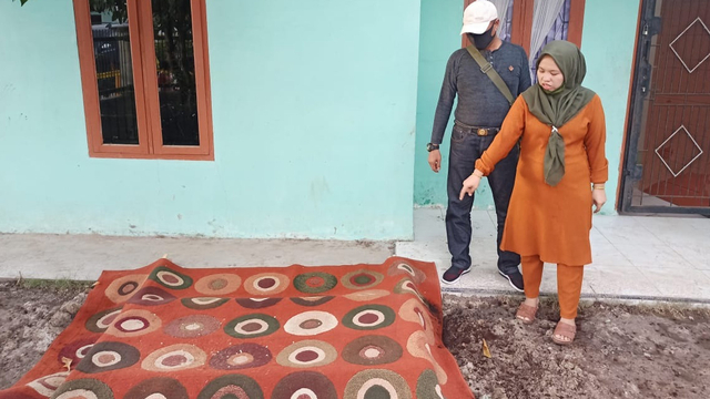 SITI Nurhasanah, adik Almarhumah Siti Hamidah, wanita hamil 6 bulan, menunjuk lubang septic tank yang ditutupi karpet depan rumah kakaknya. 