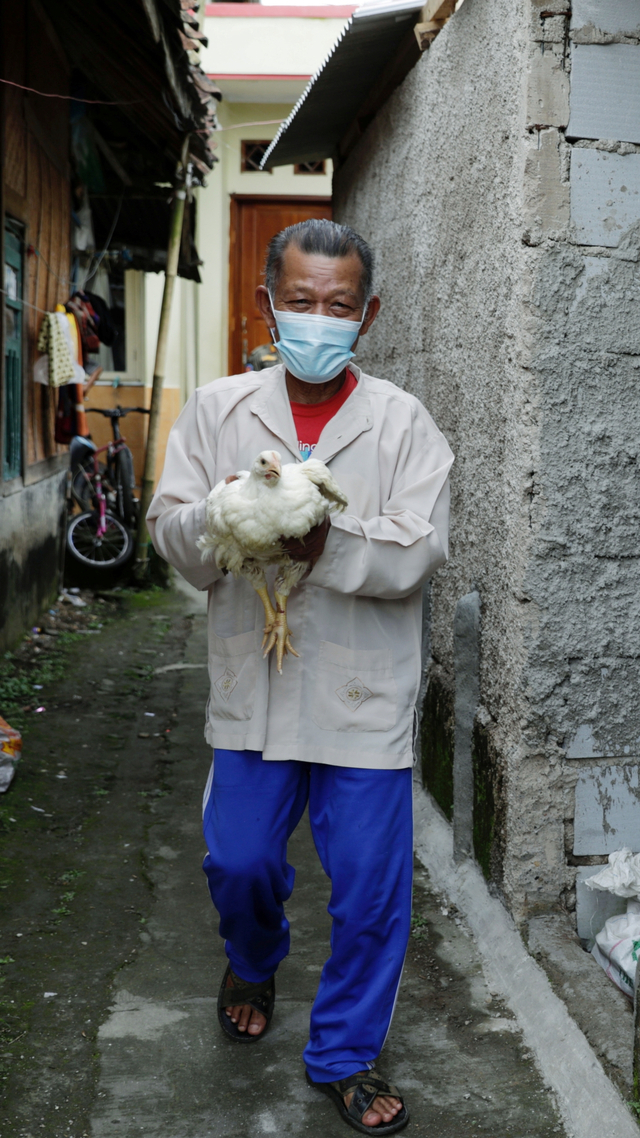 Seorang warga membawa ayam hidup yang diberi usai disuntik vaksin corona di Desa Sindanglaya, Cianjur, Selasa (15/6). Foto: Willy Kurniawan/REUTERS