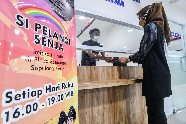 Petugas Imigrasi Kelas I Non TPI Jakarta Pusat menyerahkan paspor milik pemohon saat pelaksanaan program Imigrasi Hadir di Plaza Semanggi Sepulang Kerja (Si Pelangi Senja). Foto: Muhammad Adimaja/Antara Foto