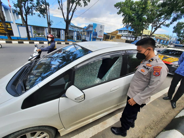 Anggota kepolisian saat memeriksa kondisi mobil korban usai jadi korban perampokan dengan modus pecah kaca mobil. Foto: Deden Saputra/kendarinesia.