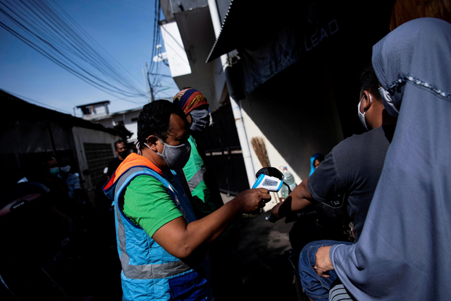 Warga memeriksa suhu tubuh pesepeda motor yang melintas masuk ke zona merah COVID-19 RT 006 RW 01, Gandaria Selatan, Cilandak, Jakarta Selatan, Senin (21/6/2021). Foto: Sigid Kurniawan/Antara Foto