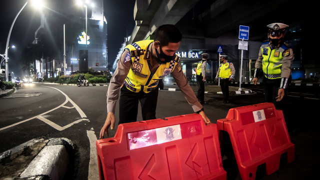 Petugas kepolisian menyusun pembatas jalan saat akan melakukan penutupan jalan di kawasan Bulungan, Jakarta, Senin (21/6/2021). Foto: Muhammad Adimaja/ANTARA FOTO