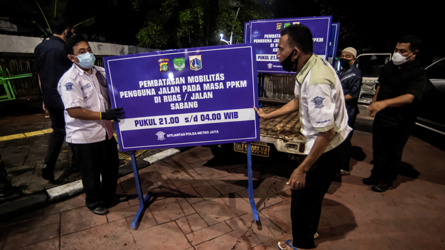 Petugas kepolisian meletakkan papan informasi saat melakukan penutupan jalan di kawasan Bulungan, Jakarta, Senin (21/6/2021). Foto: Muhammad Adimaja/ANTARA FOTO