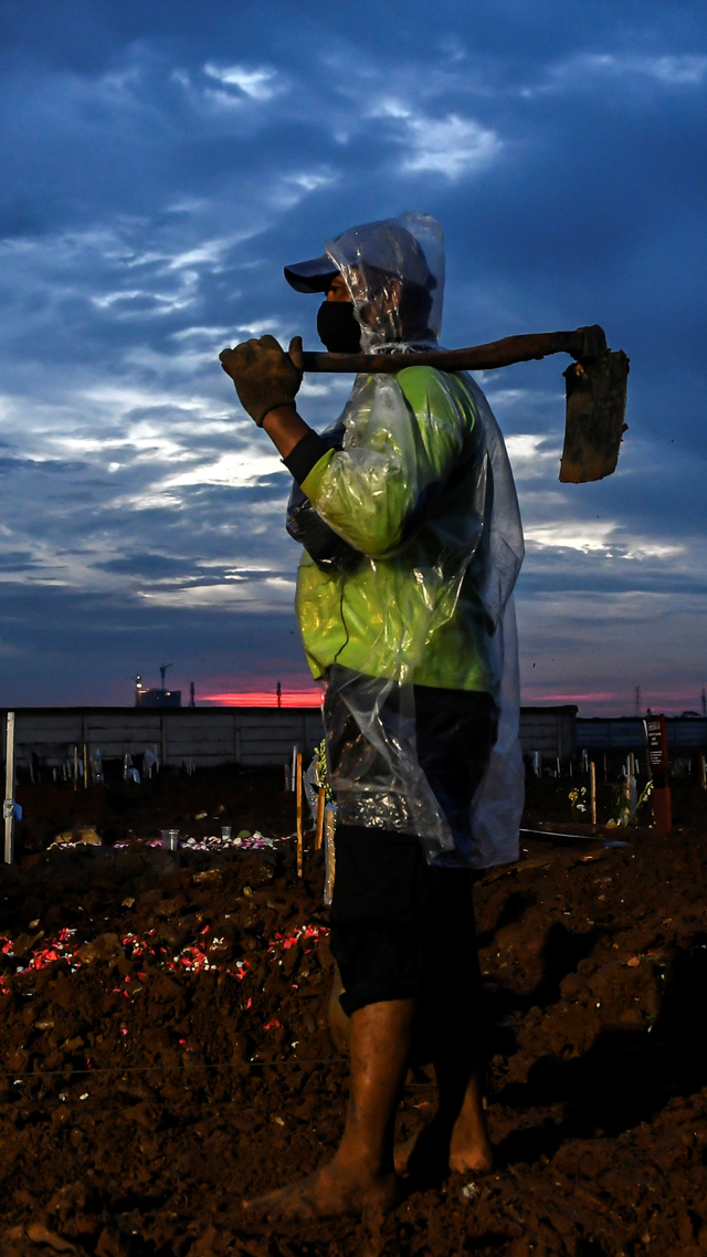 Petugas memanggul cangkul di area pemakaman jenazah dengan protokol COVID-19 di TPU Rorotan, Cilincing, Jakarta Utara, Senin (21/6/2021). Foto: M Risyal Hidayat/ANTARA FOTO