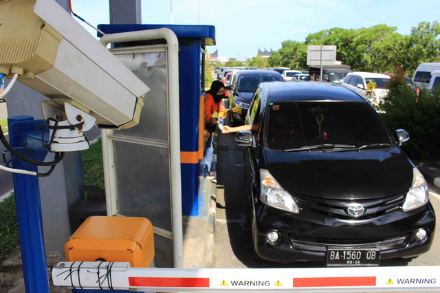 Salah seorang sales dari BNI tengah memberikan penjelasakan kepada pengendara terkait pemberlakuan transaksi non tunai di gerbang masuk Bandara Internasional Minangkabau, Selasa 22 Juni 2021. Foto: Langkan/Kumparan