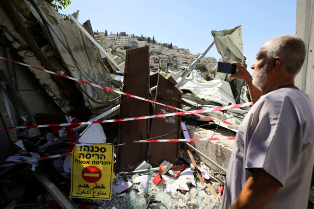 Seorang pria Palestina melihat puing-puing sebuah toko yang dihancurkan Israel di lingkungan Palestina di kawasan Silwan, Yerusalem Timur. Foto: Ammar Awad/Reuters