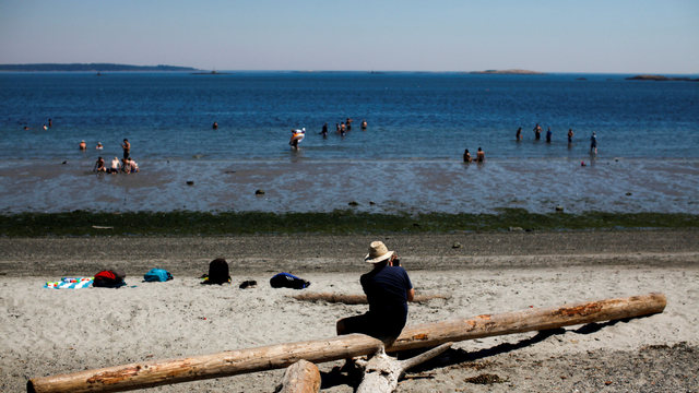 Orang-orang mencari cara untuk mendinginkan diri di Pantai Willow di Vancouver, British Columbia, Kanada, Senin (28/6). Foto: Chad Hipolito/REUTERS