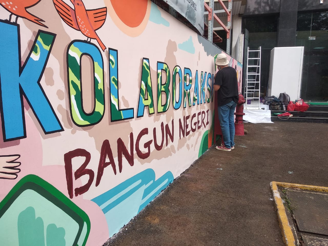 Seorang Voulenteer dari DDV melakukan aksi mural mengajak masyarakat untuk bersama-sama kolaborAksi dalam upaya bangun negeri dari keterpurukan selama pandemi Covid-19. (Rabu, 30/06/2021) Sumber: Dompet Dhuafa.