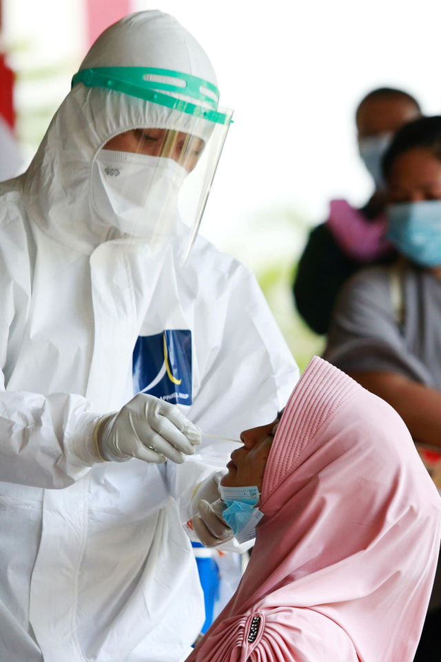 Seorang petugas kesehatan mengambil sampel swab dari seorang wanita di sebuah sekolah di Jakarta, Jumat (2/7). Foto: Ajeng Dinar Ulfiana/REUTERS