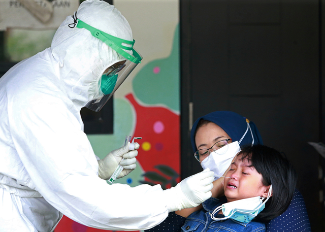 Seorang petugas kesehatan mengambil sampel swab dari seorang anak perempuan di sebuah sekolah di Jakarta, Jumat (2/7). Foto: Ajeng Dinar Ulfiana/REUTERS