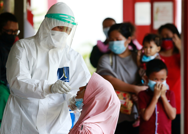 Seorang petugas kesehatan mengambil sampel swab dari seorang wanita di sebuah sekolah di Jakarta, Jumat (2/7). Foto: Ajeng Dinar Ulfiana/REUTERS