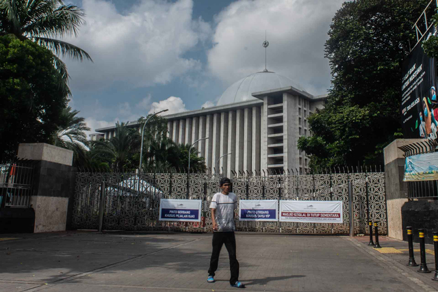 Warga berjalan di depan pintu masuk Masjid Istiqlal yang ditutup sementara untuk pelaksanaan shalat rawatib dan shalat jumat di Jakarta, Jumat (2/7/2021). Foto: Aprillio Akbar/ANTARA FOTO