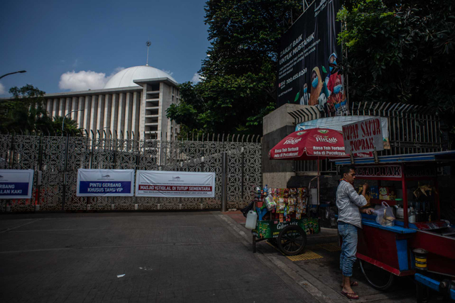 Pedagang beraktivitas di depan pintu masuk Masjid Istiqlal yang ditutup sementara untuk pelaksanaan salat rawatib dan salat jumat di Jakarta, Jumat (2/7/2021). Foto: Aprillio Akbar/ANTARA FOTO