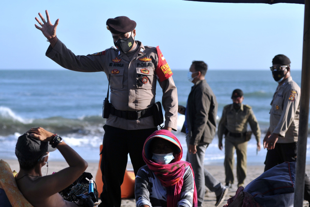 Petugas Satpol PP dan Polisi meminta wisatawan untuk meninggalkan objek wisata pantai yang ditutup saat melakukan pengawasan Pemberlakuan Pembatasan Kegiatan Masyarakat (PPKM) Darurat di kawasan Canggu, Badung, Bali, Minggu (4/7).  Foto: Fikri Yusuf/ANTARA FOTO