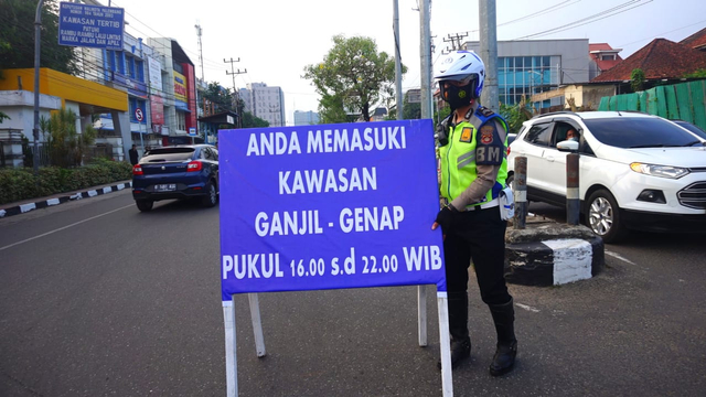 Petugas kepolisian mulai memasang papan peringatan berlakuknya skema ganjil-genap kendaraan di Palembang. (foto: Ary Priyanto/Urban Id)