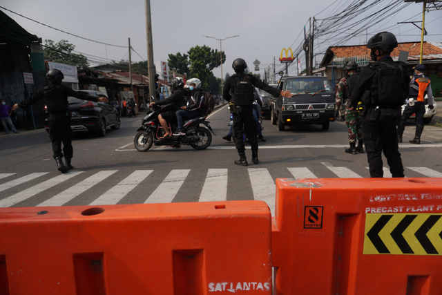 Petugas mengatur lalulintas saat penyekatan di perbatasan Jakarta-depok pada pelaksanaan PPKM darurat. Foto: Jamal Ramadhan/kumparan