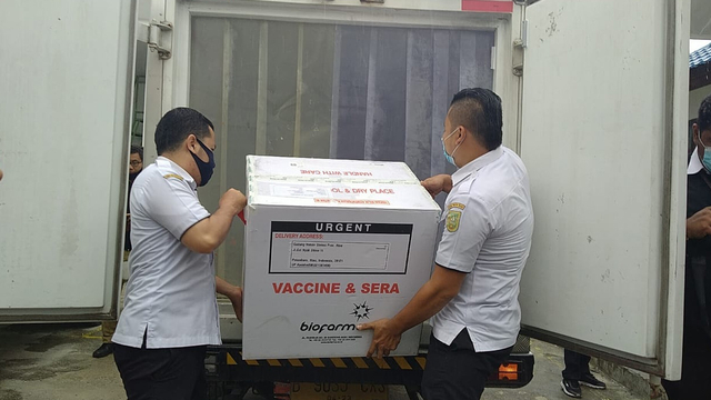 PETUGAS sedang memindahkan vaksin yang baru saja tiba di Pekanbaru. 