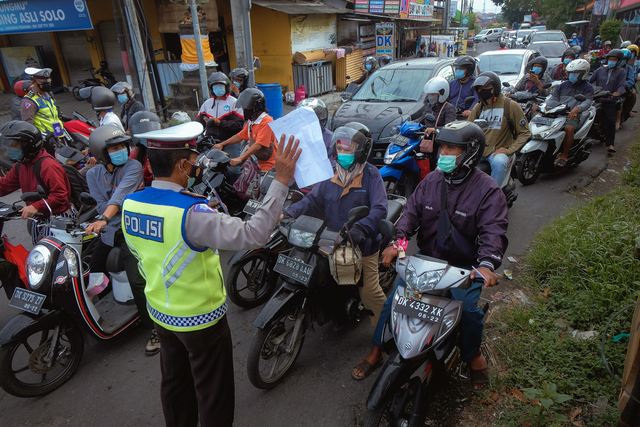 Anggota Polisi meminta warga untuk menunjukkan surat keterangan kerja saat penyekatan PPKM Darurat di Pos Teuku Umar Barat-Gunung Salak, Denpasar, Bali, Kamis (8/7/2021). Foto: Nyoman Hendra Wibowo/ANTARA FOTO