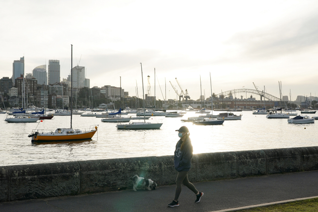 Seorang wanita mengenakan masker pelindung berjalan di sepanjang jalur tepi laut selama lockdown di Sydney, Australia. Foto: REUTERS/Loren Elliott