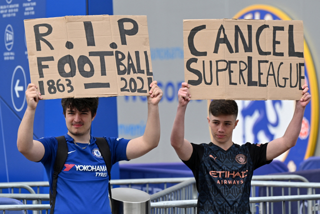 Fans Manchester City dan Chelsea memegang poster penolakan European Super League di di Stamford Bridge, London, Inggris. Foto: JUSTIN TALLIS / AFP