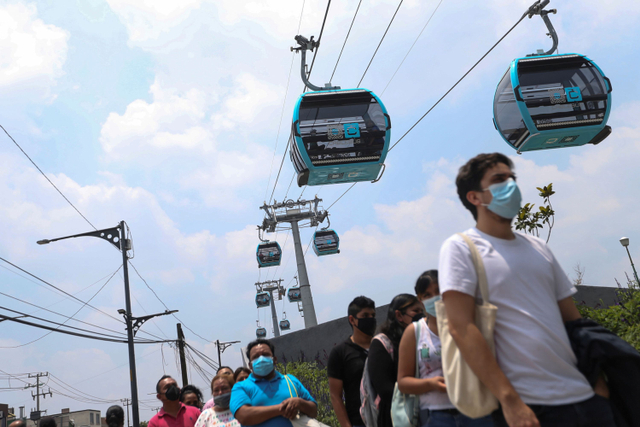 Sejumlah penumpang mengenakan masker berbaris sebelum memasuki kereta gantung yang dijuluki Cablebus di Mexico City, Meksiko. Foto: Edgard Garrido/REUTERS