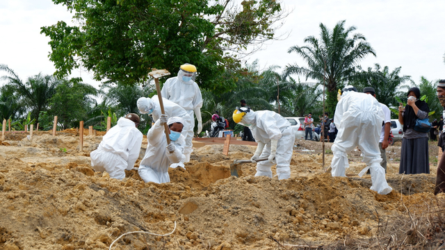 PARA pekerja penggali kuburan atau makam di Tempat Pemakaman Umum (TPU) Tengku Mahmud saat menguburkan pasien positif COVID-19.