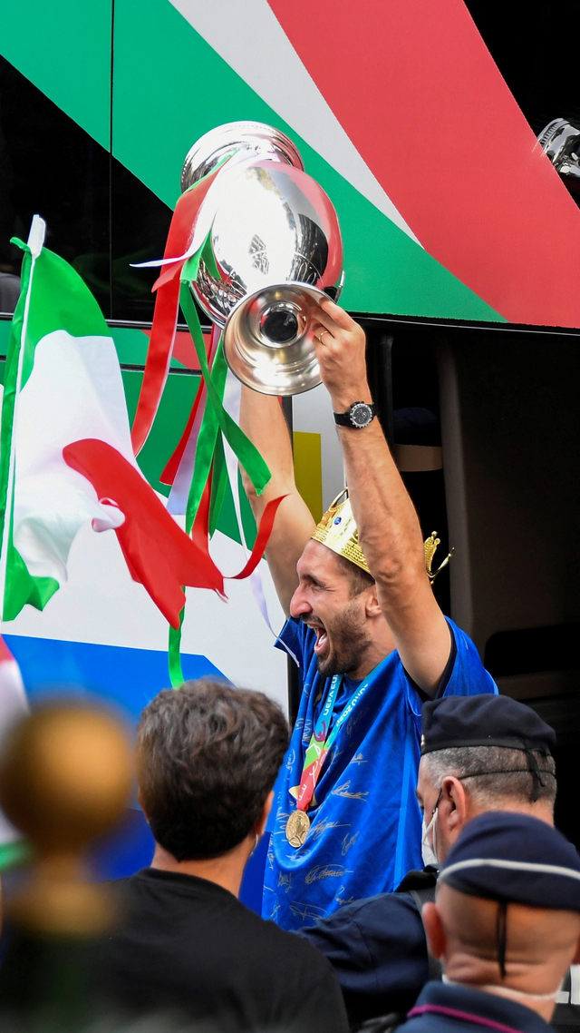 Giorgio Chiellini dari Italia keluar dari bus sambil memegang piala Euro 2020 setibanya di hotel Parco dei Principi, Roma, Italia, Senin (12/7). Foto: Alberto Lingria/REUTERS