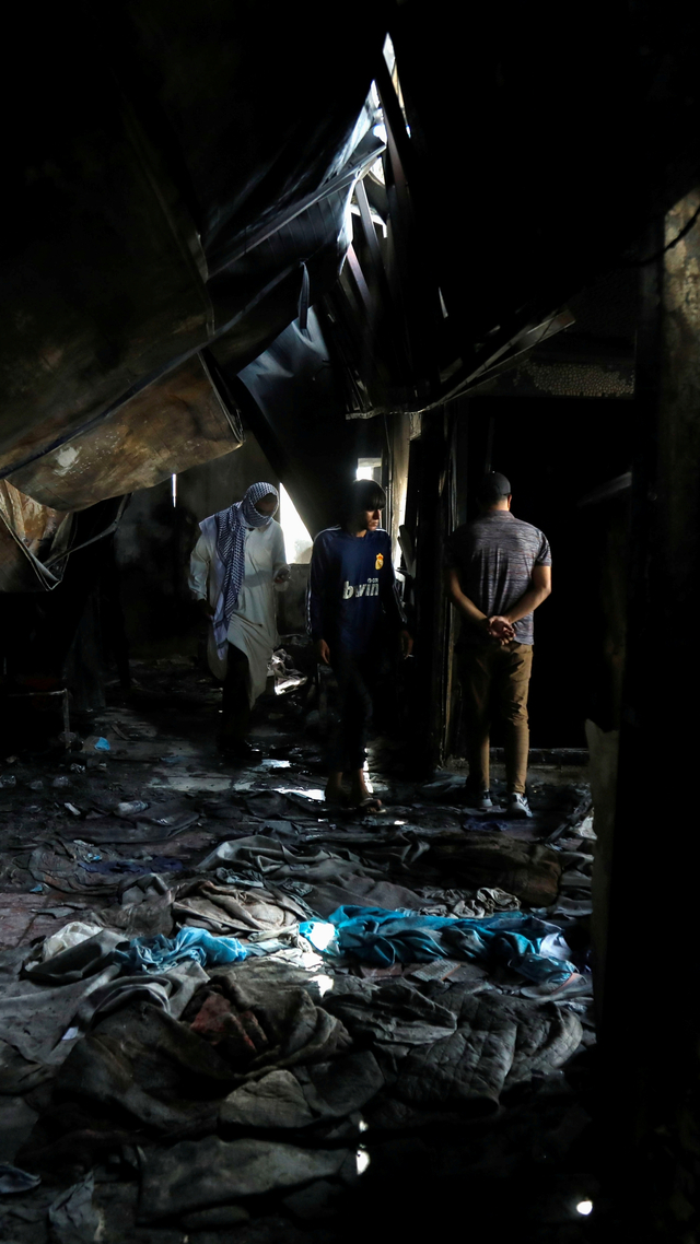 Orang-orang memeriksa kerusakan di rumah sakit virus corona al-Hussain tempat kebakaran terjadi, di Nassiriya, Irak, Selasa (13/7). Foto: Khalid al-Mousily/REUTERS