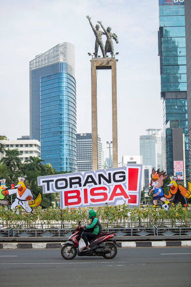 Pengendara sepeda motor melintas di dekat maskot dan slogan PON XX Papua di Bundaran Hotel Indonesia, Jakarta, Rabu (14/7/2021). Foto: Aditya Pradana Putra/ANTARA FOTO