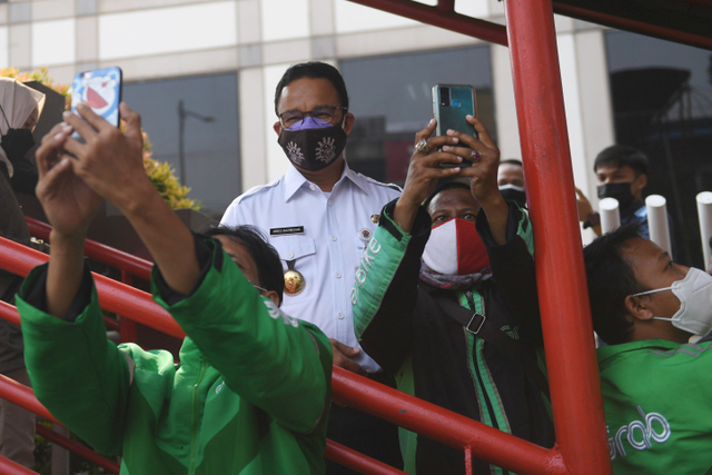 Gubernur DKI Jakarta Anies Baswedan melayani permintaan swafoto pengemudi ojek daring usai memantau titik penyekatan baru di Mampang, Jakarta, Kamis (15/7).  Foto: Akbar Nugroho Gumay/ANTARA FOTO