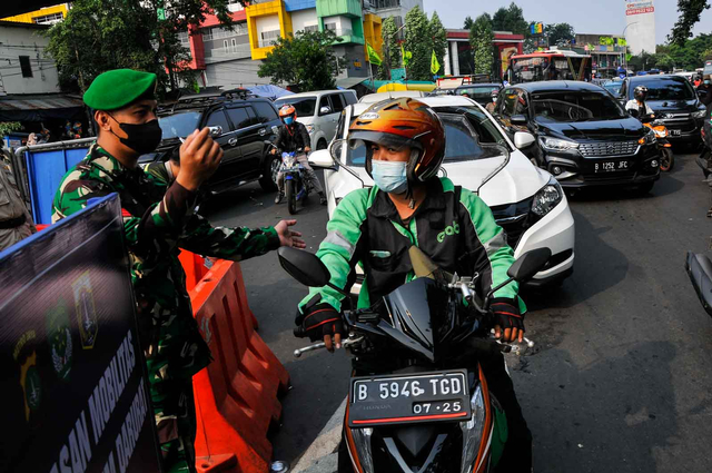 Prajurit TNI mengarahkan pengendara ojek daring untuk mencari jalan alternatif saat akan melintasi titik penyekatan PPKM Darurat di Jalan Jendral Basuki Rahmat, Jakarta Timur, Kamis (15/7/2021). Foto: Fakhri Hermansyah/ANTARA FOTO