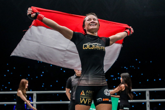 Atlet MMA Priscilla Hertati Lumban Gaol merayakan kemenangan di atas ring dengan membawa bendera Indonesia. Foto: ONE Champioship
