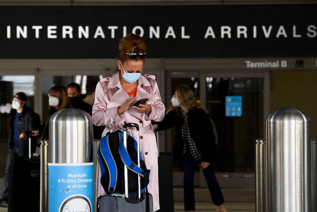 Seorang warga memakai masker saat tiba di Bandara Internasional Los Angeles (LAX), Los Angeles, California, Amerika Serikat.  Foto: Patrick T. FALLON / AFP