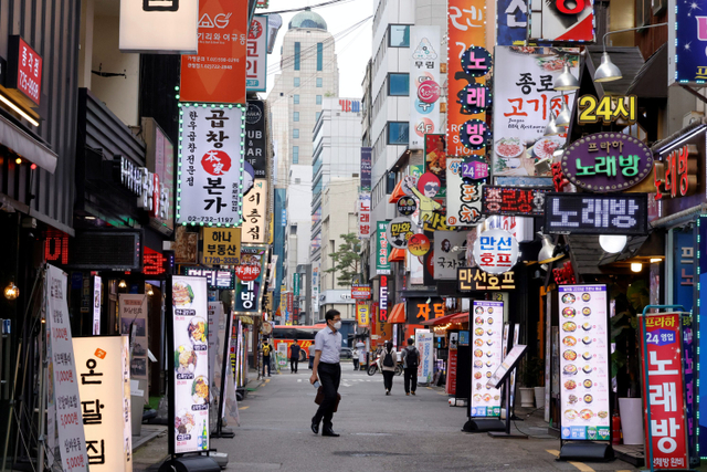 Seorang warga memakai masker di tengah ketatnya aturan jarak sosial di Seoul, Korea Selatan.
 Foto: Heo Ran/REUTERS