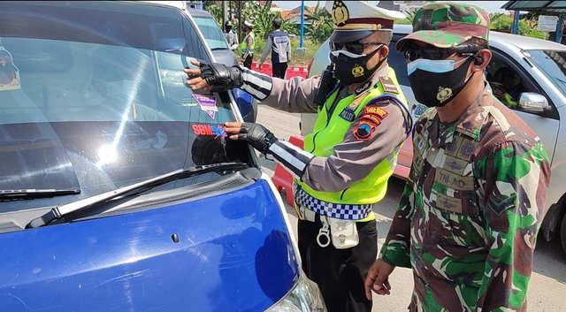 Polisi memasang stiker pada kendaraan yang masuk sektor esensial dan kritikal. 