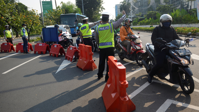 Polisi mengarahkan pengendara sepeda motor saat akan melintas di titik penyekatan baru di kawasan Gerbang Pemuda, Jakarta Selatan, Jumat (16/7/2021). Foto: M Risyal Hidayat/ANTARA FOTO